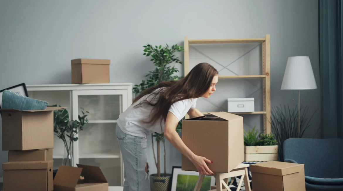 Woman carrying moving boxes in a living room