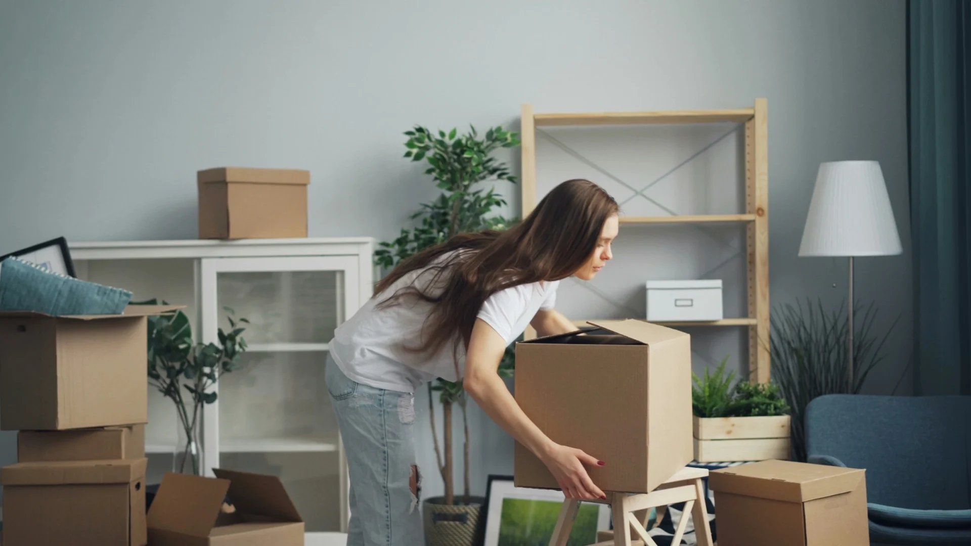 Woman moving boxes in a living room | Warrington Van Hire | Central Warrington Van Hire | Call 01925 396 222 Woman carrying moving boxes in a living room