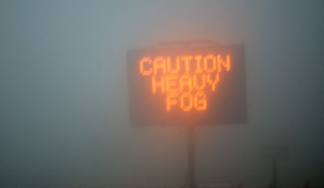 A professional Warrington Van Hire vehicle with illuminated fog lights navigating a misty road safely according to the Highway Code.
