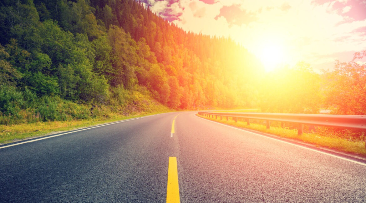 A driver using a sun visor while driving a hire van in bright sunshine on a motorway, illustrating safe vision management to reduce solar glare.