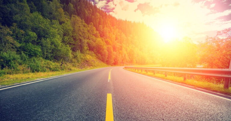 A driver using a sun visor while driving a hire van in bright sunshine on a motorway, illustrating safe vision management to reduce solar glare.