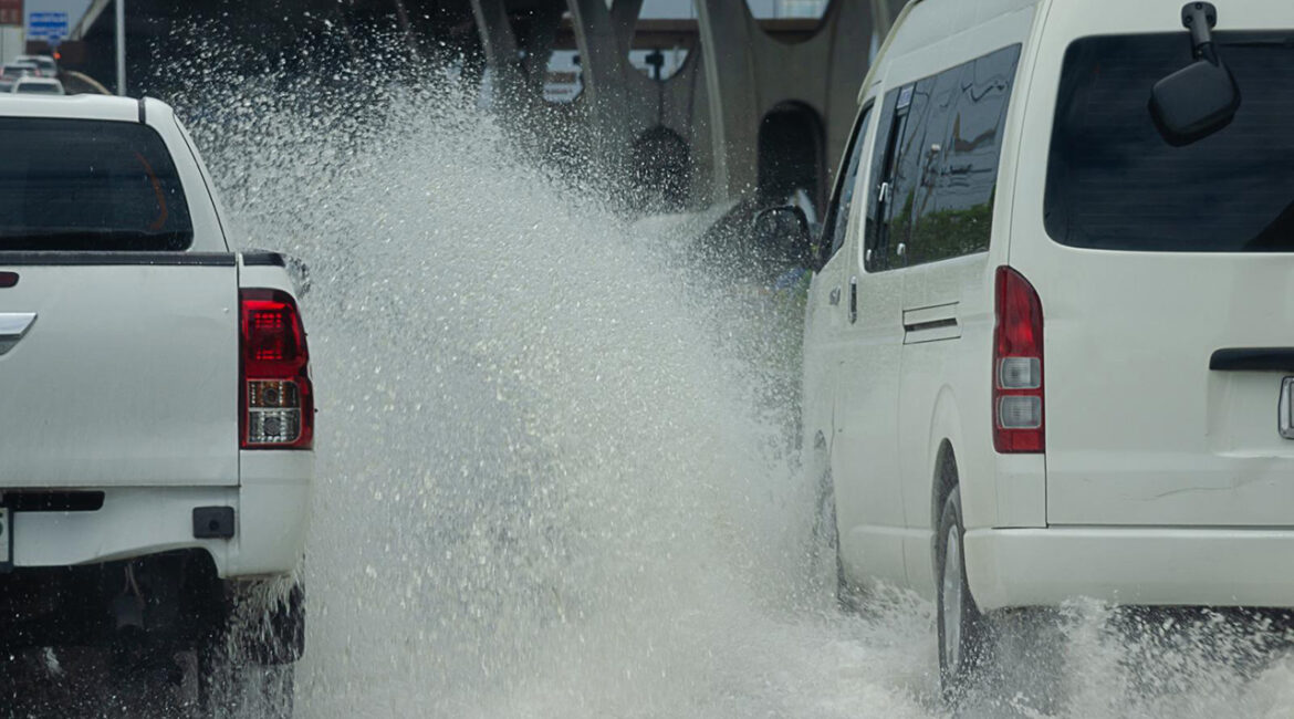 A professional rental van carefully navigating a large puddle, demonstrating safe driving techniques for flooded roads this autumn in the UK.