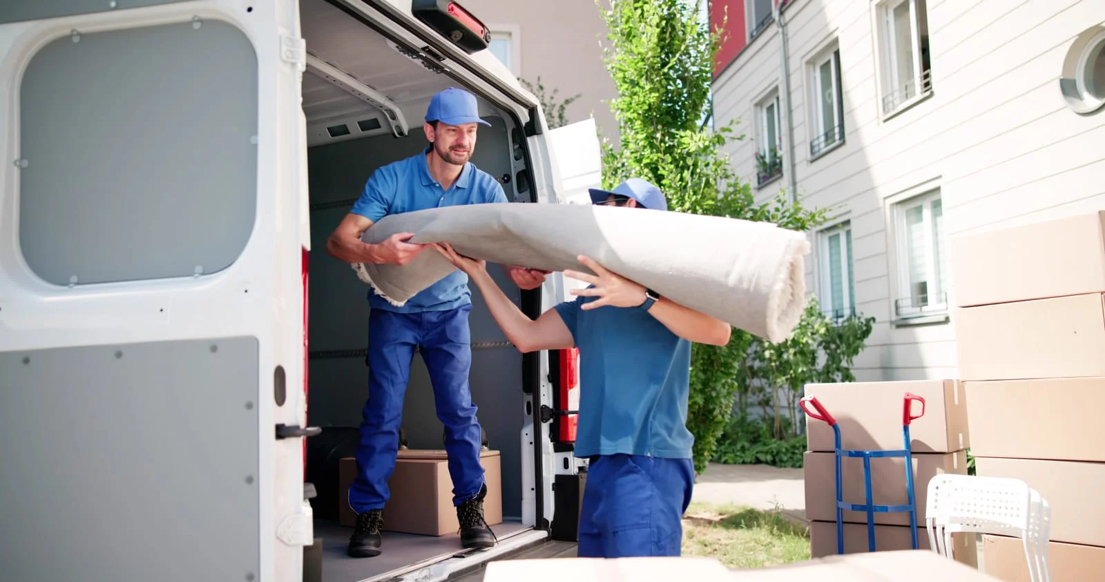 Two people carrying furniture from a house clearance