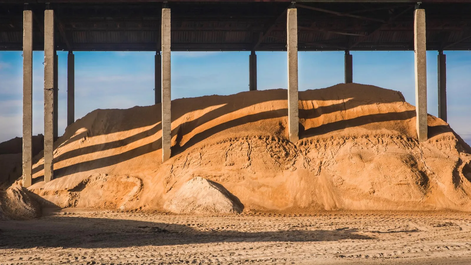 Sand and aggregate stored under a canopy at a supplier yard, ready for bulk bag collection