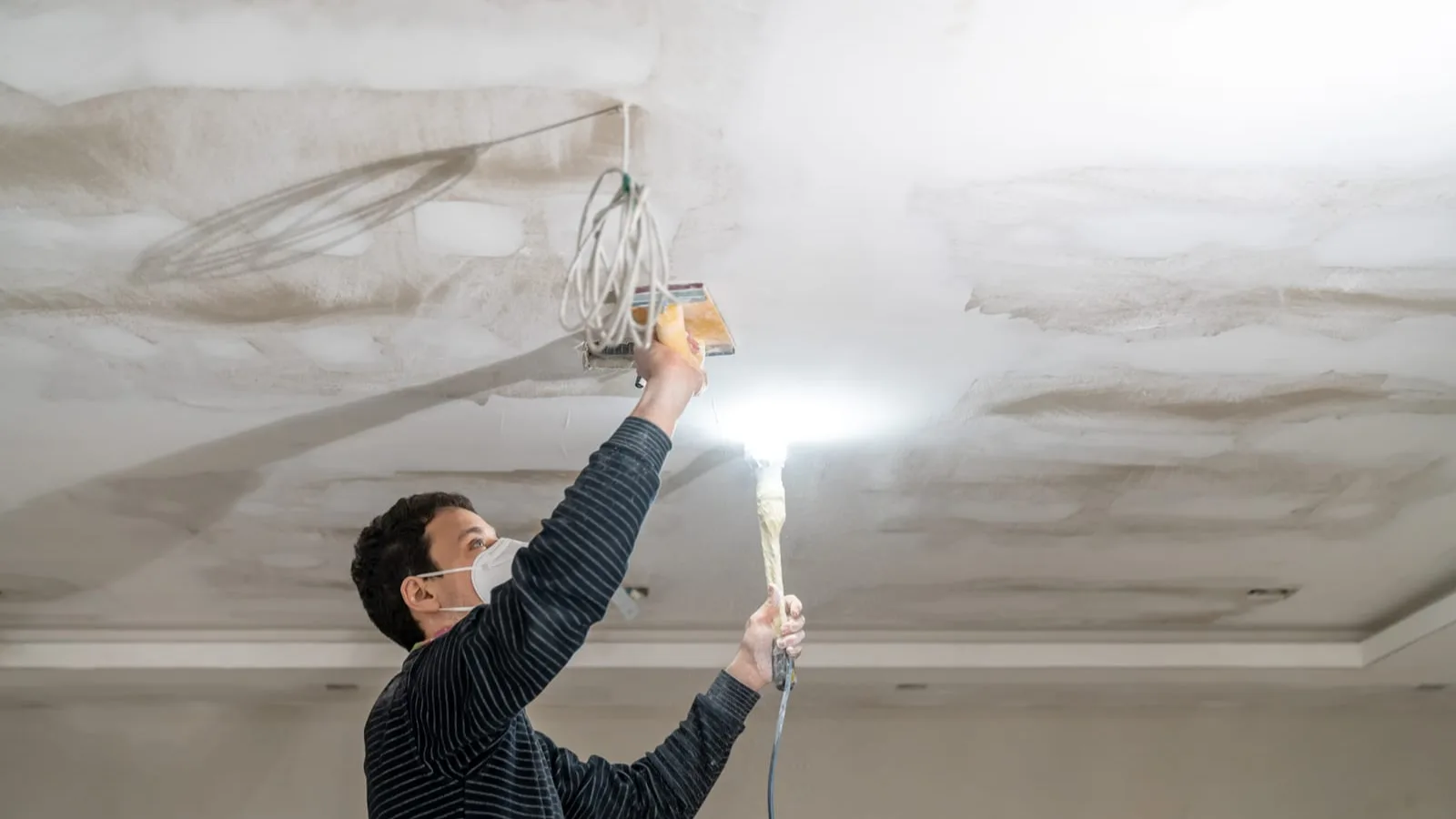 Worker finishing a plasterboard ceiling, the end of a job that starts with plasterboard van hire